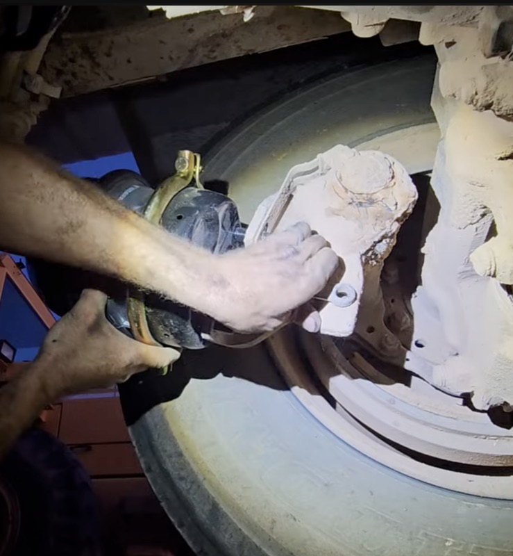 Mechanic performing brake chamber repair on a heavy-duty truck axle