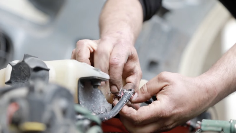 Close-up of mechanic reconnecting a coolant line on a semi truck
